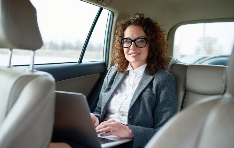 A businesswoman working from her black car ride
