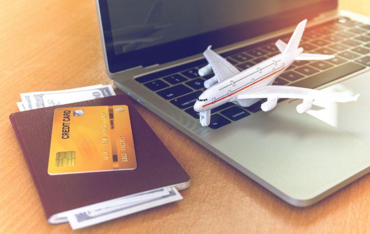 A computer, toy plane, a passport and credit card on a table