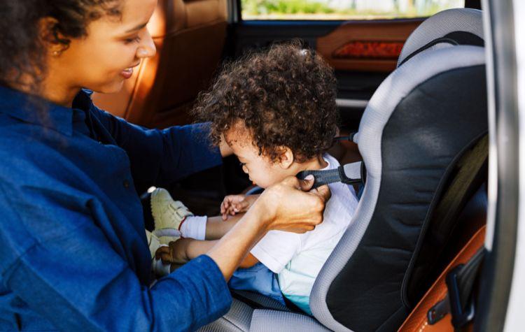 A mother buckling her child into the backseat of a car service