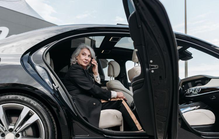 A woman on the phone in back of a luxury car
