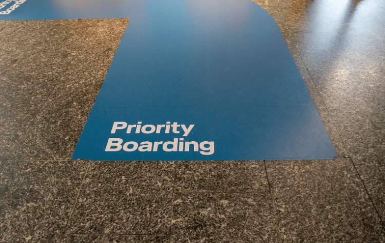 Blue priority boarding lane painted on airport terminal floor leading to plane boarding