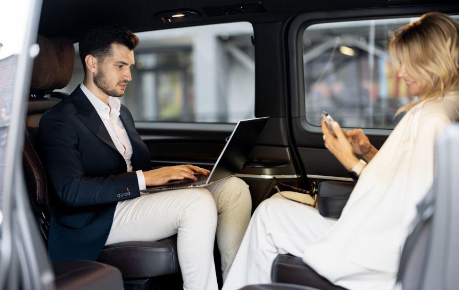 Business travelers getting work done in their black car transfer